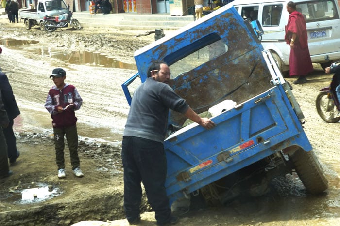 A truck is stuck in a giant hole due to the poor muddy road conditions